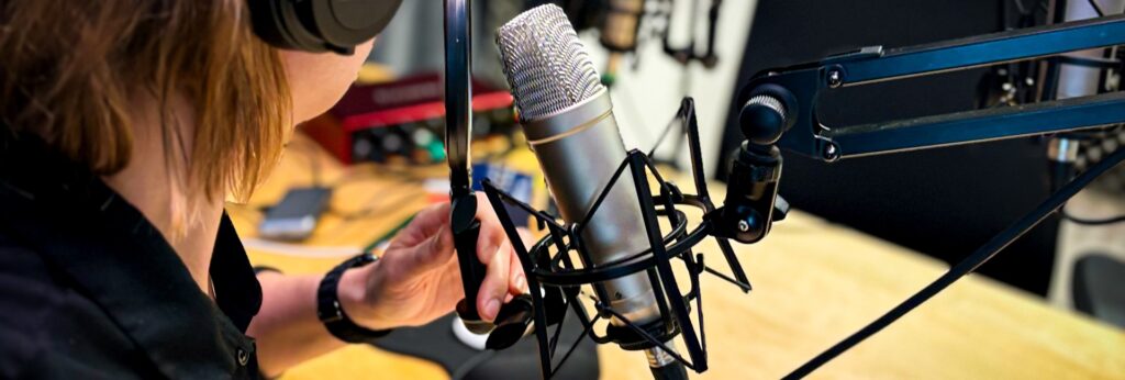 En person som pratar in i en poddmikrofon. 